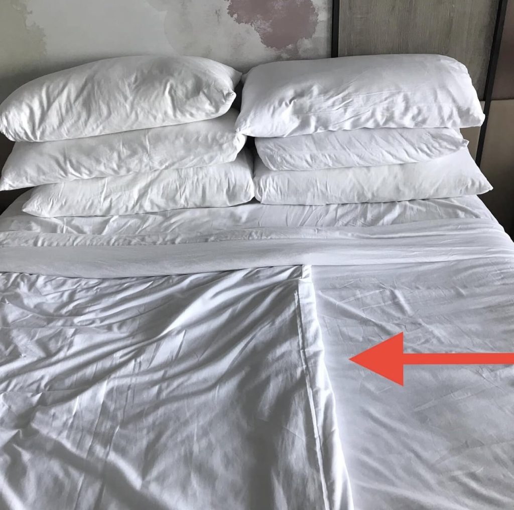 Picture of a cruise cabin bed made up with the duvet on only one half of the bed